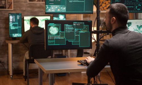 Back view of dangerous team of hackers working on a new malware.