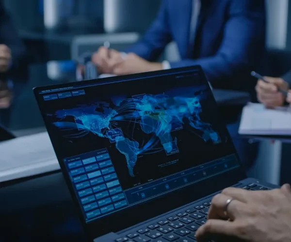On the Table Laptop Showing World Data Flow: Team of Politicians, Corporate Business Leaders and Lawyers Sitting at the Negotiations Table in the Conference Room, Trying to Come to an Agreement.